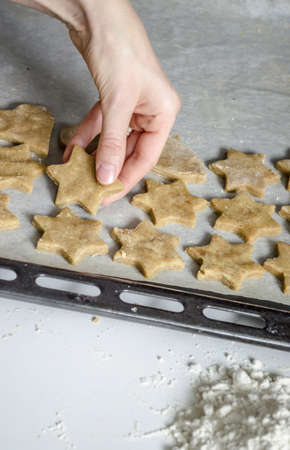 Photo of womans hand putting christmas cookies on a baking pan の写真素材