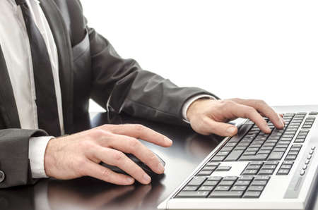 Closeup of a businessmans hands typing on keyboard on a black desk の写真素材