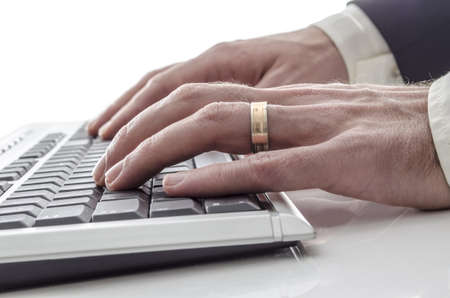 Businessmans hands typing on keyboard on a white table の写真素材
