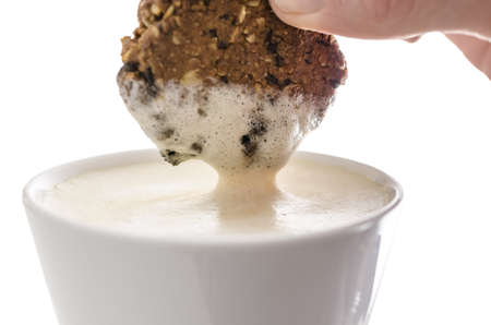 Closeup of a hand dipping a cookie in cocoa  Isolated over white background の写真素材