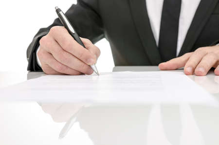 Front view of a business man signing a contract  With reflection on a white table の写真素材