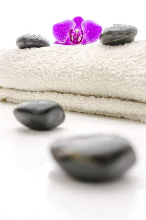Massage stones and violet orchid flower on a towel  Focus on a flower の写真素材