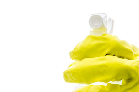 Hand in a yellow rubber glove holding a spray bottle towards you  With copy space の写真素材