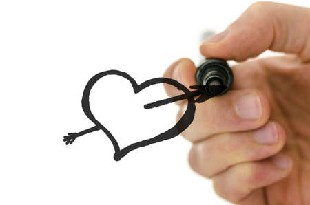 Detail of male hand drawing heart shape pierced with sharpe arrow on a glass board.の写真素材