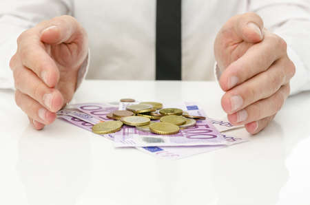 Male hands around Euro banknotes and coins as if they are giving power and energy to money.