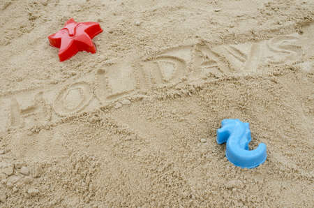 Word holiday written in sand. Concept of summer holidays.