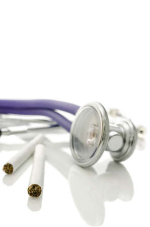 Closeup of two cigarettes and stethoscope isolated over white  Shallow depth of field 