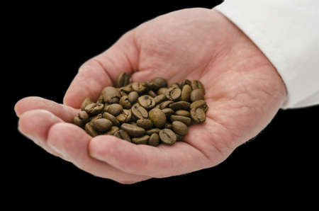Male hand holding coffee grains isolated over black background.の写真素材