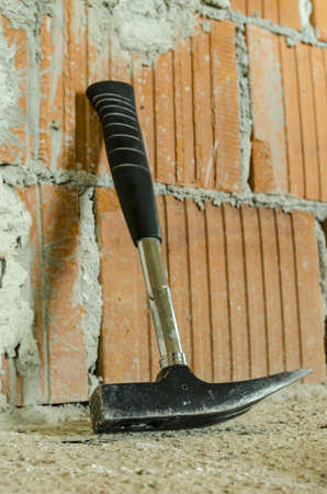 Hammer leaning on brick wall on construction site. Concept of building a house.の写真素材
