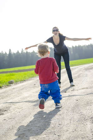 Son running to his mother who is waiting for him with open hands の写真素材