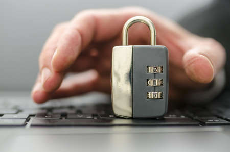 Male hand stealing padlock off computer keyboard.の写真素材