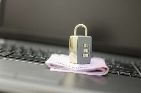 Padlock on money placed on laptop keyboard. Concept of safety of online banking.の写真素材