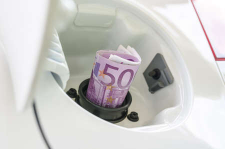Euro money in car fuel tank opening representing expensive gas or fuel の写真素材