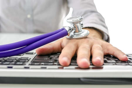 Stethoscope on businessman hand using computer representing work addict の写真素材