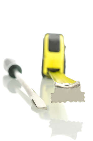 Screwdriver and measuring tape on white desk with reflection. Isolated over white background.の写真素材