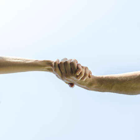 Bottom view of handshake over clear blue sky.
