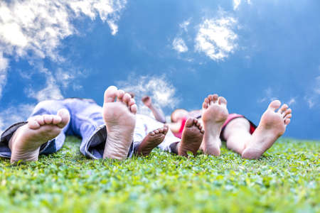 Young family enjoying life lying in green grass on a beautiful day の写真素材