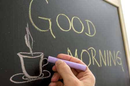 Closeup of cafe owner writing good morning sign on black board の写真素材