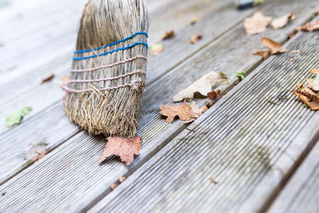 Closeup of sweeping autumn leaves off a wooden porch.の写真素材