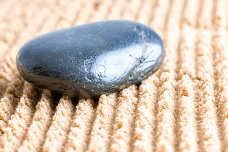 Closeup of black stone in zen garden sand.