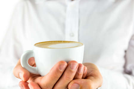 Closeup of man in white shirt holding cup of delicious fresh cappuccino.の写真素材