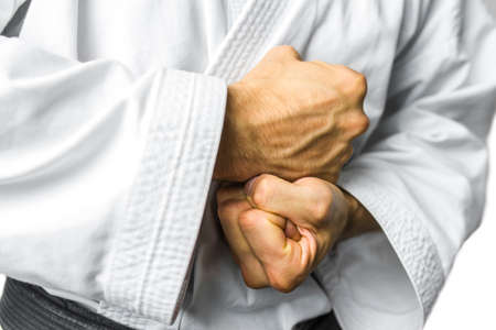 Closeup of male karate fighter in white kimono making strong fists with his hands.の写真素材
