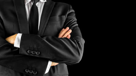 Closeup of businessman with arms crossed. Over black background.の写真素材