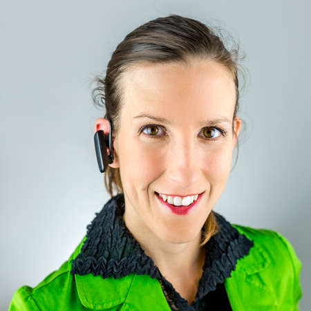 Portrait of young female call center agent with wireless headset.の写真素材