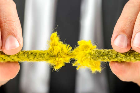 Closeup of businessman holding torn yellow rope.の写真素材