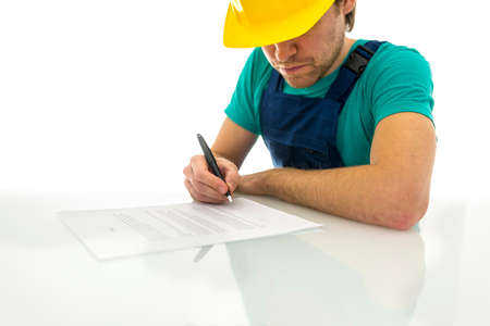 Young construction worker signing contract on white desk. Over white background.の写真素材