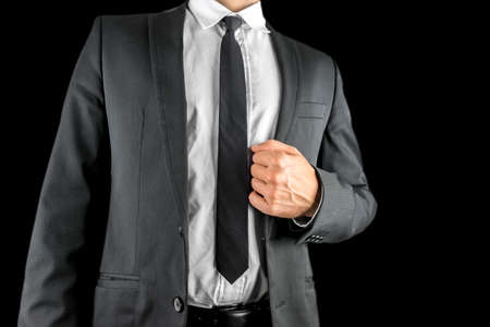Close up of the torso of a confident businessman in a suit holding the lapel of his stylish jacket in his hand conceptual of success and self-assuranceの写真素材