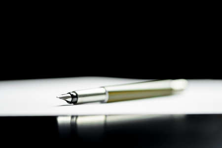 Fountain pen lying on a document with the nib towards the camera depicting writing a letter, taking...