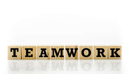 The word Teamwork on wooden cubes arranged in a line over white with copyspace above and a...
