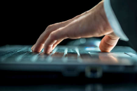 Close up low angle view of the hands of a businessman entering data on his laptop computer or navigating the webの写真素材