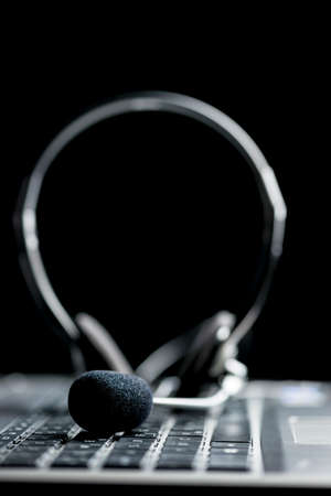 Close-up of a stereo headset on the keyboard of a computer, on black backgroundの写真素材