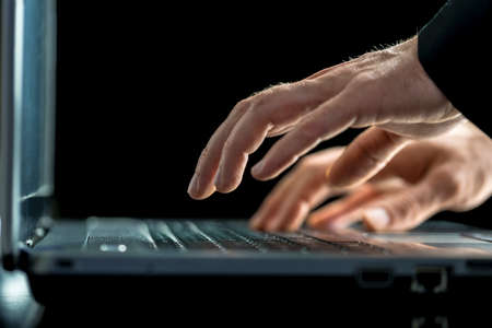 Businessman typing on his laptop computer entering information or answering correspondence
