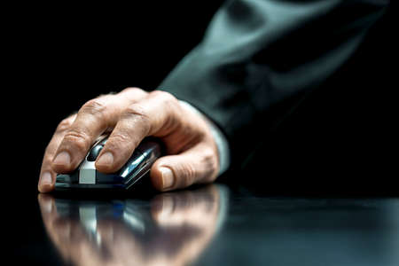 Closeup of the hand of a businessman using a computer mouse to browsing the internetの写真素材