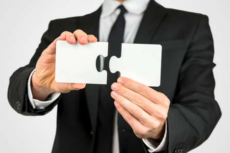 Businessman holding two blank white puzzle pieces in his hands conceptual of solving a problem, growth and development.の写真素材