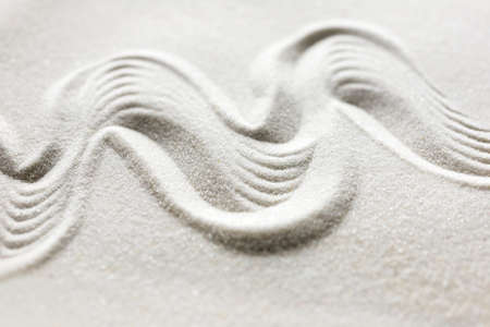 Organic wavy undulating pattern drawn in a Japanese yen garden, landscaped rock garden or raked sand with a grainy texture and flowing motion conceptual of tranquility and spirituality.の写真素材