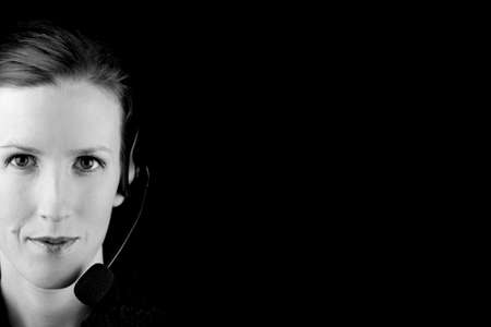 Monochromatic black and white image of an attractive young woman wearing a headset with copyspace to...