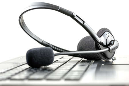 Headset lying on a laptop computer keyboard conceptual of telemarketing, call center, client services or online support. Headset lying on a laptop computer keyboard conceptual of telemarketing, call center, client services or online support.
