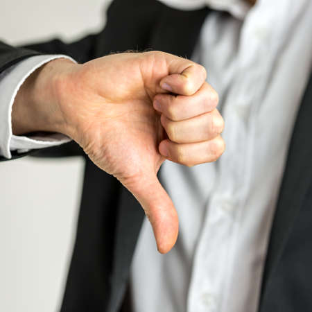 Man giving a thumbs down gesture of disapproval showing his negativity and dissatisfaction, close up of his hand.の写真素材
