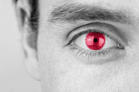 Monochrome image with selective color of a young man with red eye, close up of his eye and eyebrow.の写真素材