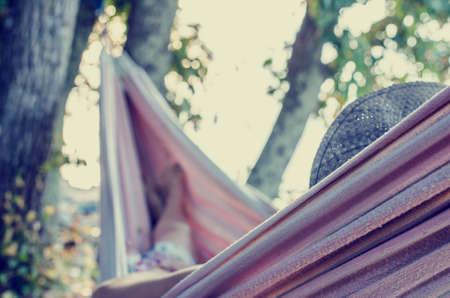  woman relaxing on a hot summer day in a hammock strung in the shade of a tree.
