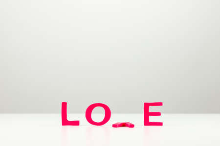 Conceptual image with word love in red letters with the V lying face down on the table.の写真素材