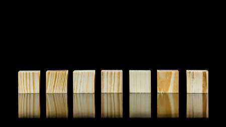 Row of seven blank wooden blocks on a black background with copyspace for your text, letters or...