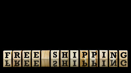 Free shipping text on a line of natural wooden cubes on a reflective black backgroundの写真素材