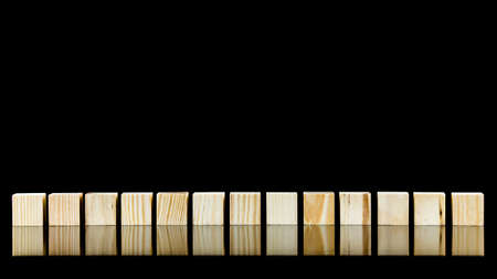 Row of thirteen blank wooden blocks on a black background with copyspace for your text, letters or numbers.の写真素材