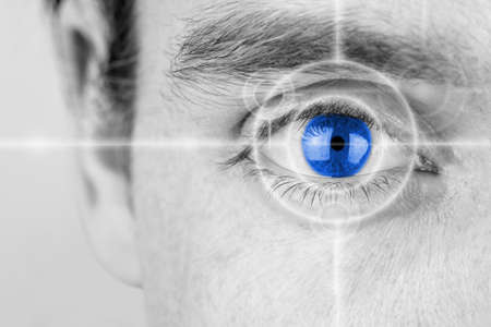 Vision concept with a greyscale image of a mans eye with a crosshair focused on his iris which has...