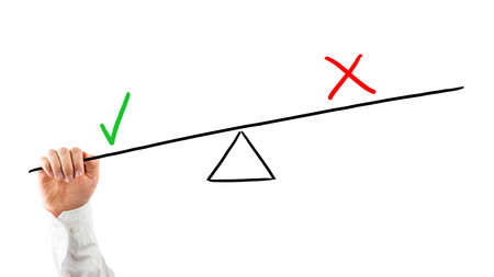 Man balancing positives against negatives reaching his hand up to a seesaw with a check mark and cross pulling down on the check mark for weighted importance, on white.の写真素材